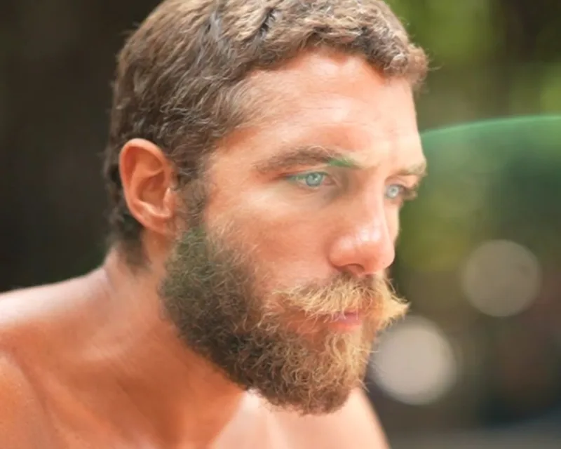 Παίκτης του Survivor με μούσια και γαλάζια μάτια σε κοντινό πλάνο.