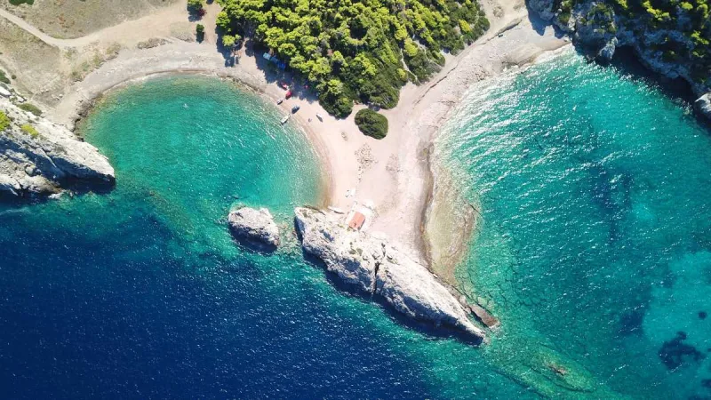 Αεροφωτογραφία παραλίας στην Πελοπόννησο με γαλαζοπράσινα νερά και πεύκα.