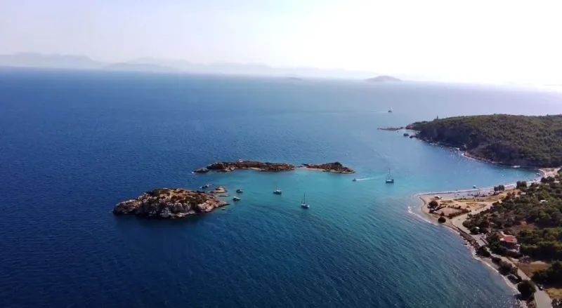 Πανοραμική άποψη της παραλίας Περιστέρια στη Σαλαμίνα με μικρά νησάκια και σκάφη.