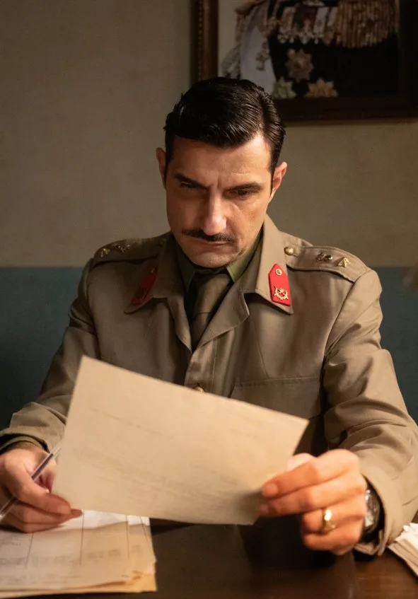 Ο Νίκος Κουρής με στρατιωτική στολή εποχής κρατάει ένα έγγραφο.