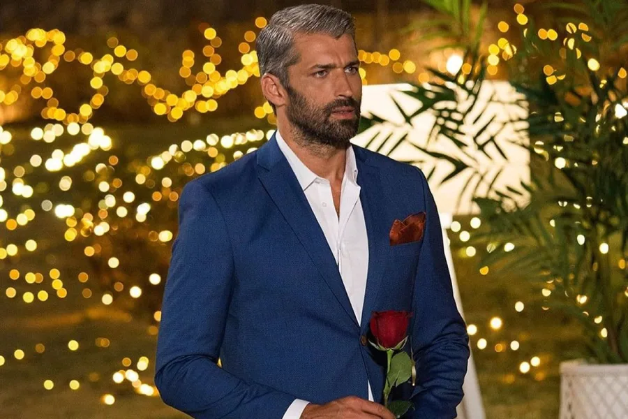 Ο Παναγιώτης Βασιλάκος από το The Bachelor κρατά ένα κόκκινο τριαντάφυλλο.