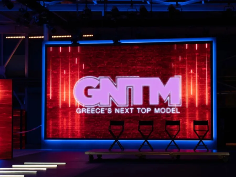 Το λογότυπο του GNTM σε μεγάλη οθόνη σε τηλεοπτικό πλατό.