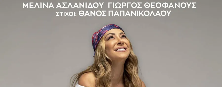 Η Μελίνα Ασλανίδου με χρωματιστό μαντήλι στα μαλλιά κοιτάζει προς τα πάνω χαμογελώντας.