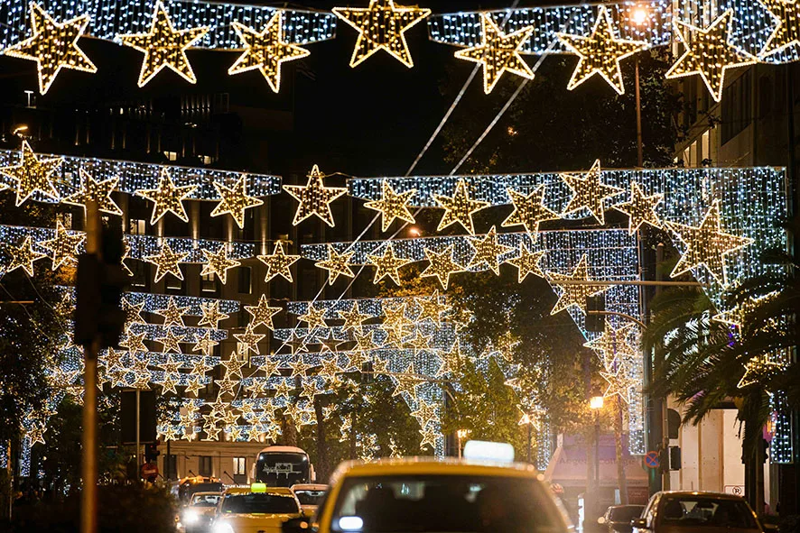 Χριστουγεννιάτικος στολισμός με φωτεινά αστέρια πάνω από δρόμο της Αθήνας τη νύχτα.
