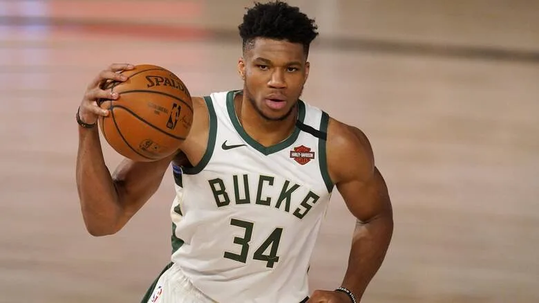 Ο Γιάννης Αντετοκούνμπο με τη φανέλα των Milwaukee Bucks κρατώντας μια μπάλα μπάσκετ.