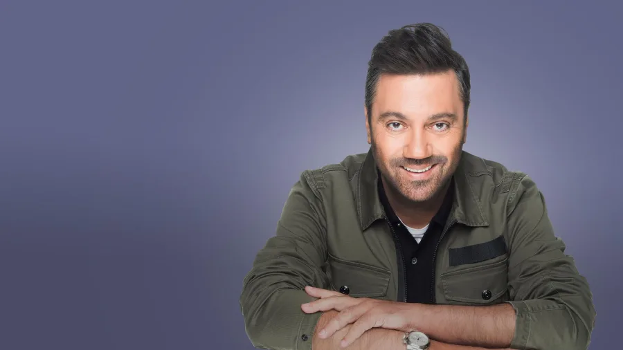 Ο Γιώργος Θεοφάνους χαμογελαστός σε στούντιο φωτογράφιση.