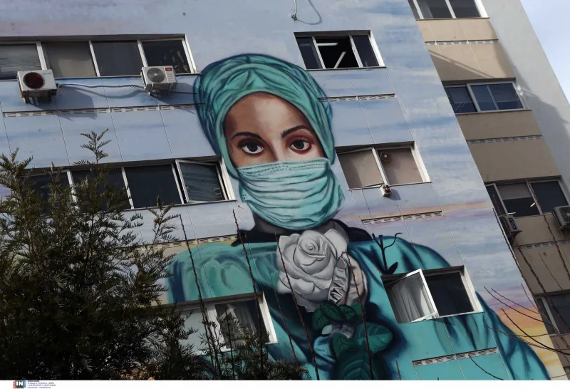 Graffiti στο Τζάνειο νοσοκομείο με νοσηλεύτρια που φοράει μάσκα και κρατάει ένα λευκό τριαντάφυλλο.