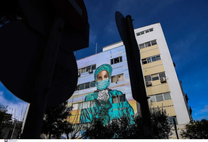 Graffiti στο Τζάνειο νοσοκομείο με νοσηλεύτρια που φοράει μάσκα και κρατάει λευκό τριαντάφυλλο.