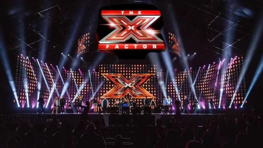 Το λογότυπο του The X Factor πάνω από μια σκηνή με πολλούς διαγωνιζόμενους.