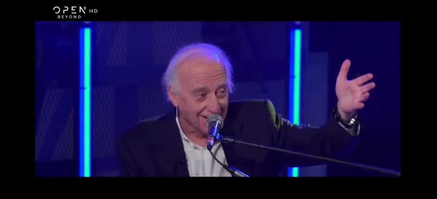 Ο Γιώργος Χατζηνάσιος μιλάει σε μικρόφωνο κατά τη διάρκεια τηλεοπτικής εκπομπής.