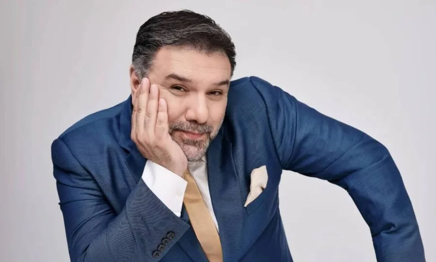 Ο Γρηγόρης Αρναούτογλου με μπλε κοστούμι σε λευκό φόντο.
