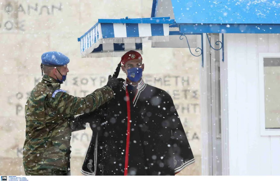 Εύζωνας με χειμερινή ενδυμασία και στρατιώτης στο Σύνταγμα κατά τη διάρκεια χιονόπτωσης.
