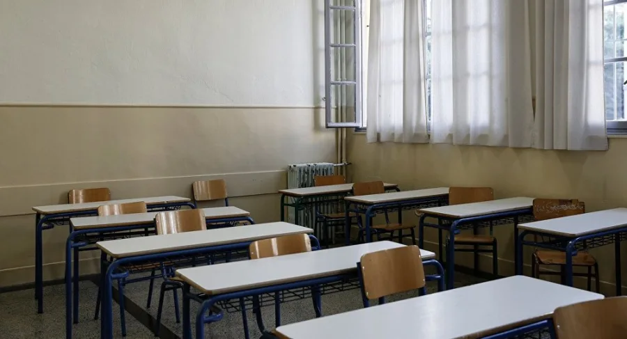 Άδεια σχολική αίθουσα με θρανία και καρέκλες.