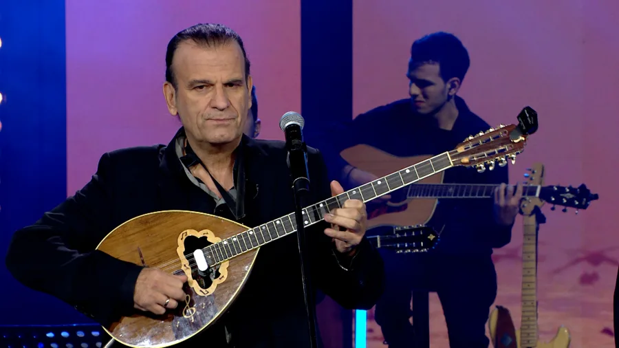 Ο Χρήστος Παπαδόπουλος παίζει μπουζούκι στη σκηνή.