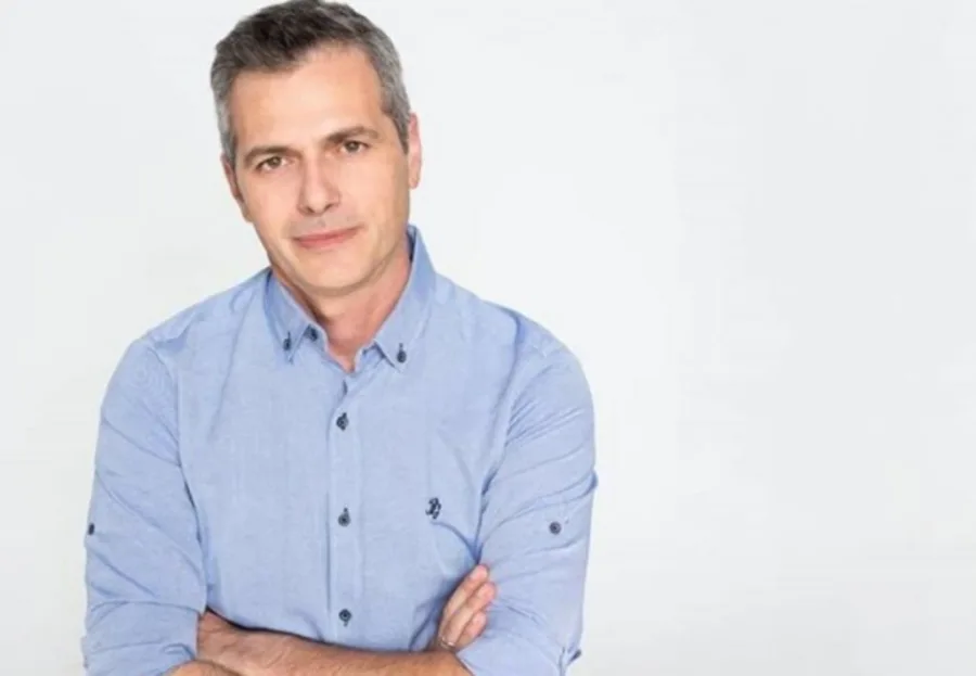Ο Μάριος Αθανασίου με γαλάζιο πουκάμισο σε λευκό φόντο.