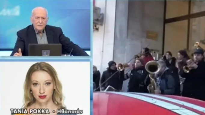 Η Τόνια Ρόκκα σε τηλεοπτική εκπομπή δίπλα σε πλάνα από μουσική μπάντα.