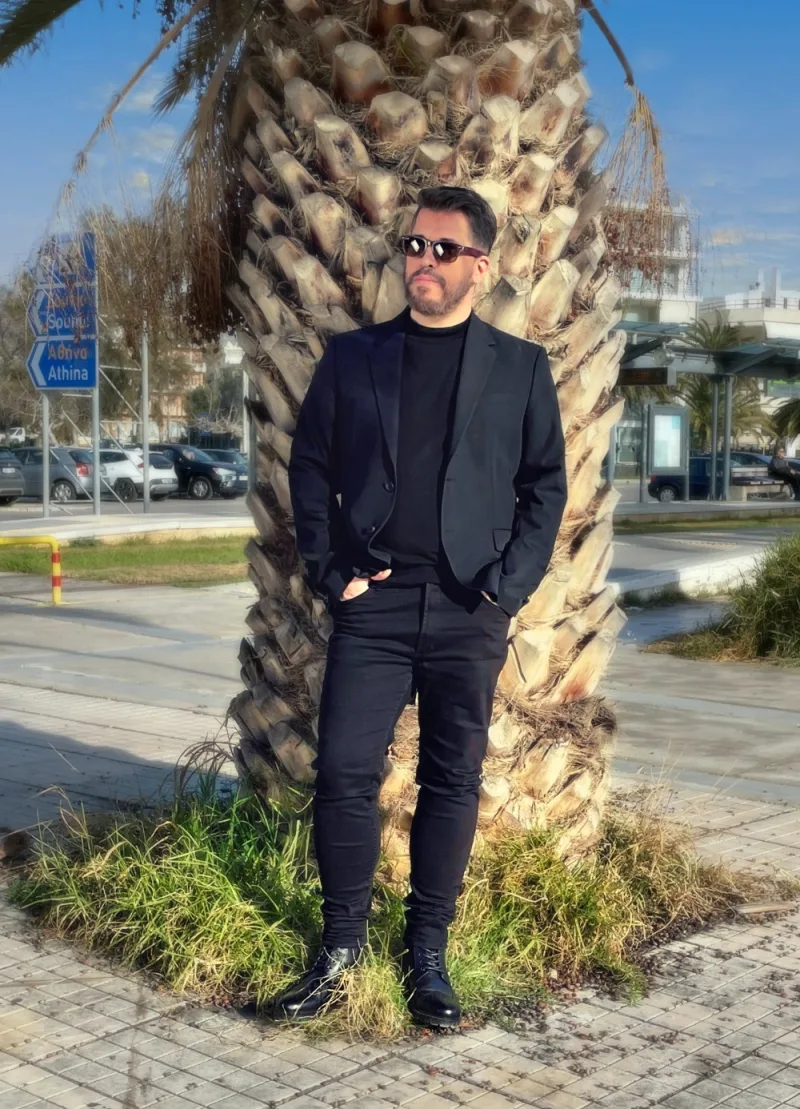 Ο Χάρης Βαρθακούρης ποζάρει μπροστά από έναν φοίνικα.