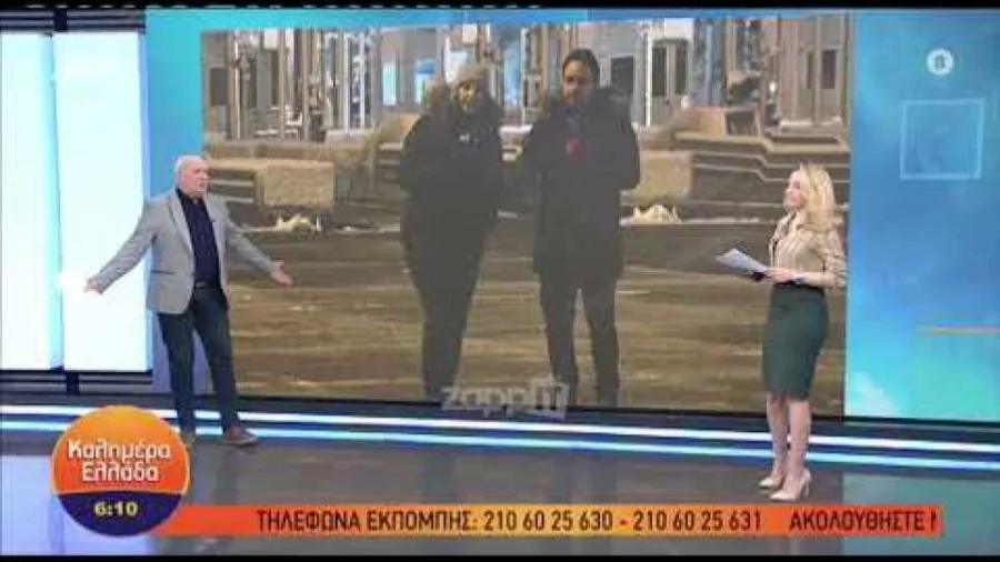 Ο Γιώργος Παπαδάκης σε τηλεοπτικό πλατό με συμπαρουσιάστρια και οθόνη σε ζωντανή σύνδεση.