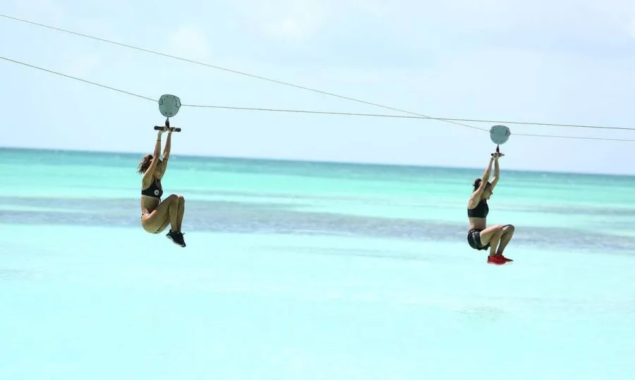 Δύο παίκτριες του Survivor σε αγώνισμα με zip line πάνω από τη θάλασσα.