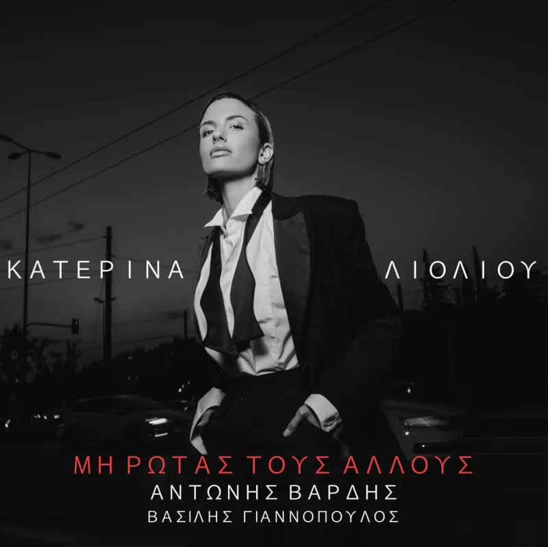 Η Κατερίνα Λιόλιου με κοστούμι και λυμένη γραβάτα σε ασπρόμαυρο φόντο.