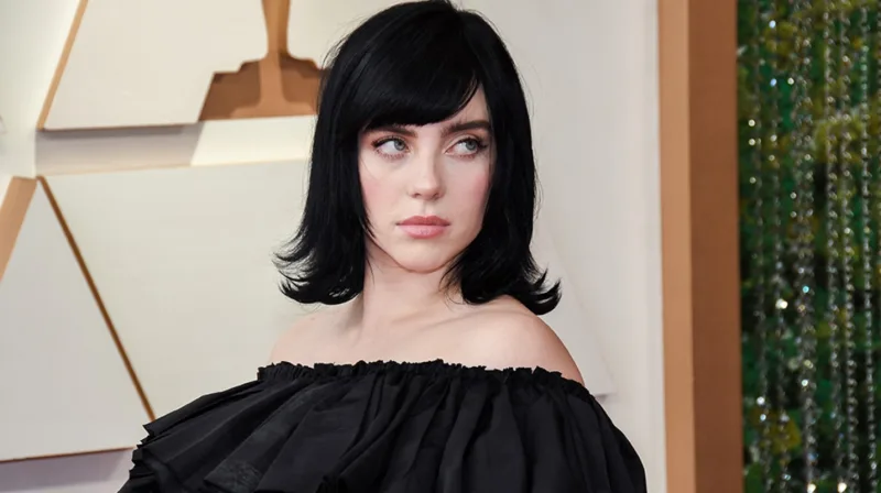 Η Billie Eilish με μαύρα μαλλιά και μαύρο φόρεμα σε επίσημη εκδήλωση.