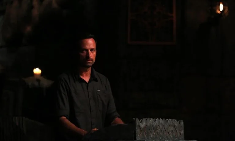 Ο παρουσιαστής του Survivor σε σκοτεινό σκηνικό συμβουλίου.