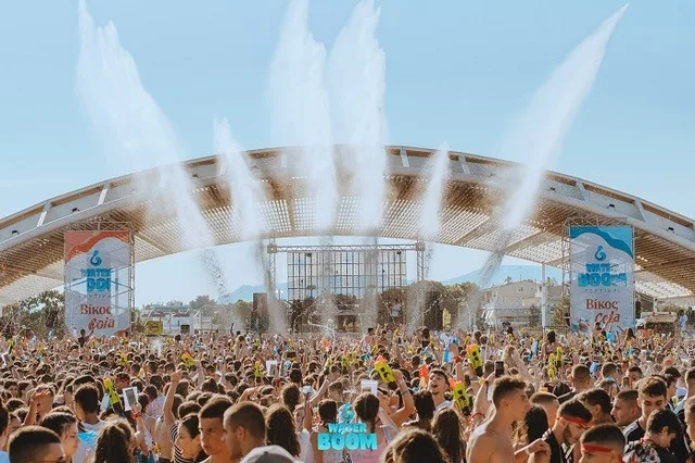 Πλήθος κόσμου στο Waterboom Festival 2022 κάτω από πίδακες νερού.