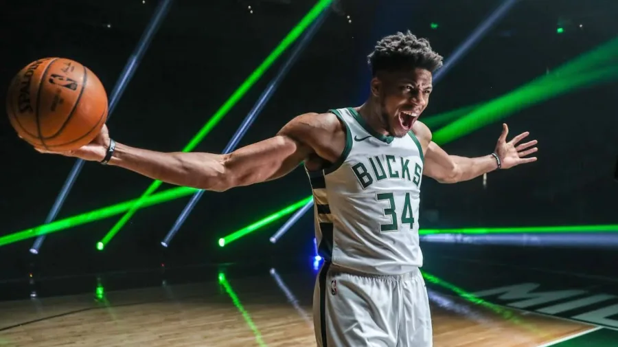 Ο Γιάννης Αντετοκούνμπο με τη φανέλα των Milwaukee Bucks κρατά μια μπάλα μπάσκετ.