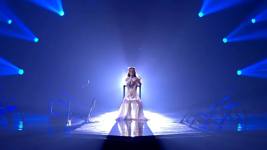 Τραγουδίστρια στη σκηνή της Eurovision 2022 με λευκό φόρεμα και μπλε φωτισμούς.