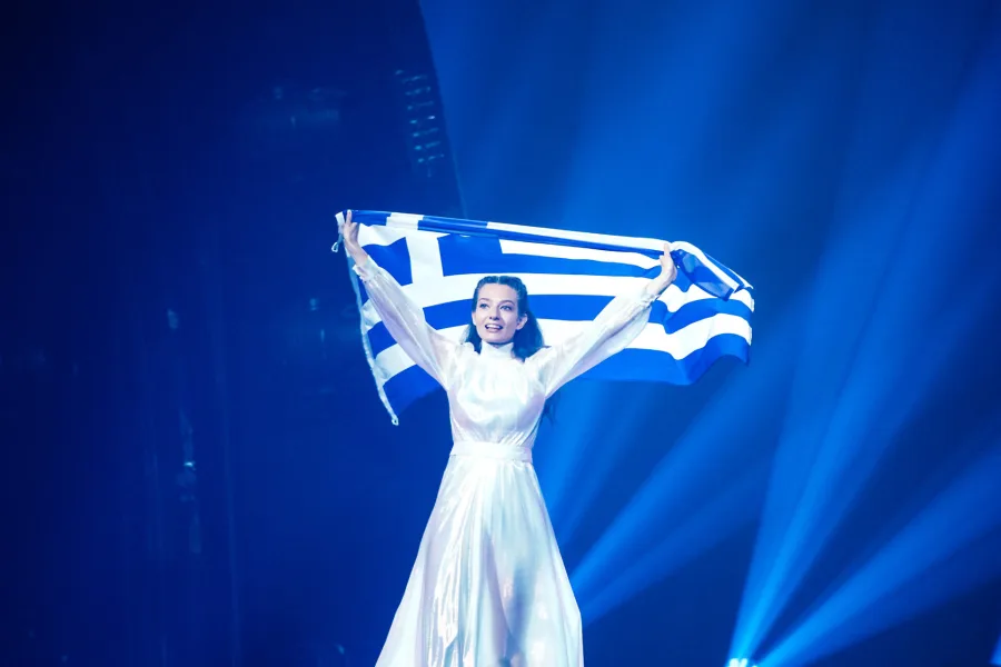 Τραγουδίστρια στη σκηνή της Eurovision κρατώντας την ελληνική σημαία.