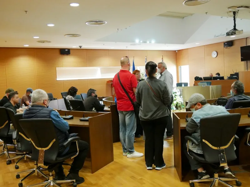 Άνθρωποι σε αίθουσα συνεδριάσεων με προστατευτικές μάσκες.
