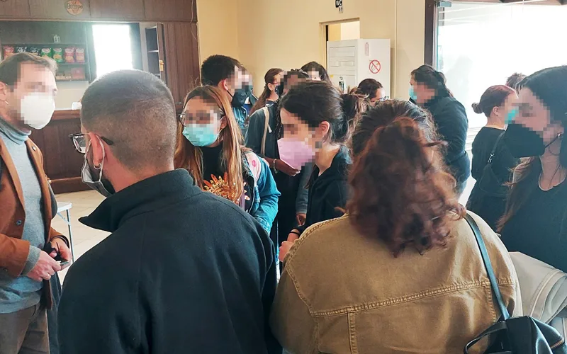 Ομάδα ανθρώπων σε εσωτερικό χώρο που φορούν προστατευτικές μάσκες προσώπου.