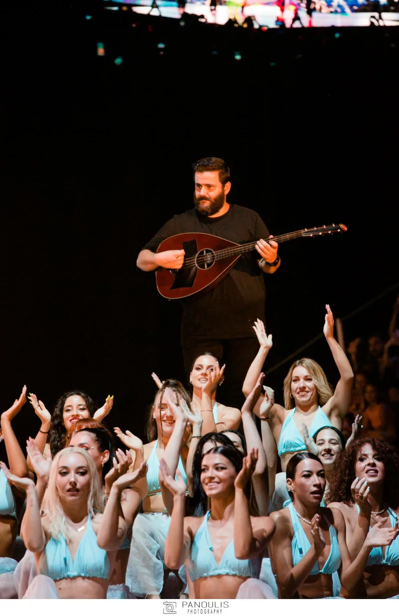 Καλλιτέχνης με έγχορδο όργανο στη σκηνή των Mad Video Music Awards 2022, πλαισιωμένος από χορεύτριες.