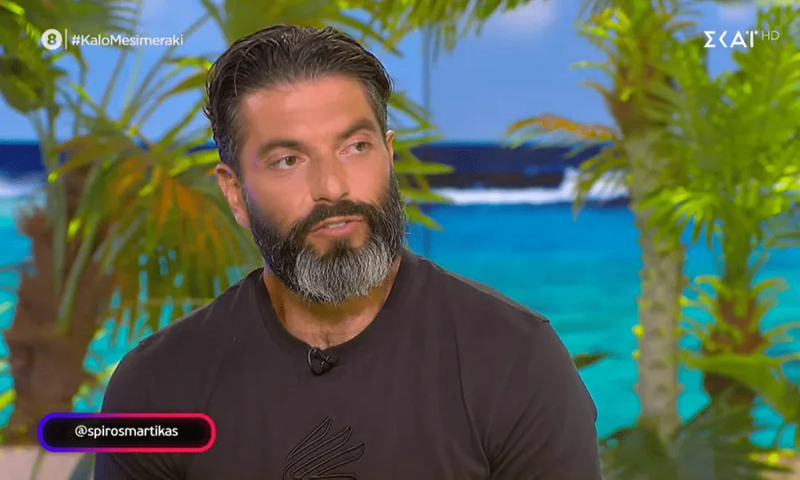 Ο Σπύρος Μαρτίκας σε τηλεοπτική εκπομπή με φόντο τροπικό τοπίο.