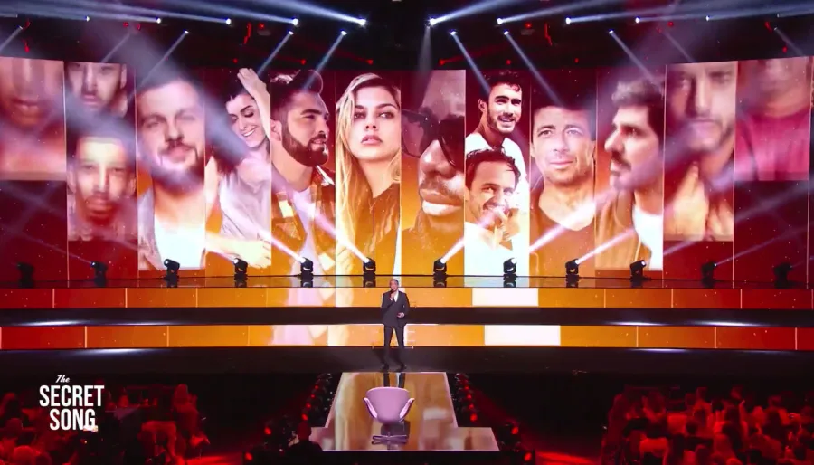 Σκηνικό του μουσικού show The Secret Song με παρουσιαστή και οθόνες.