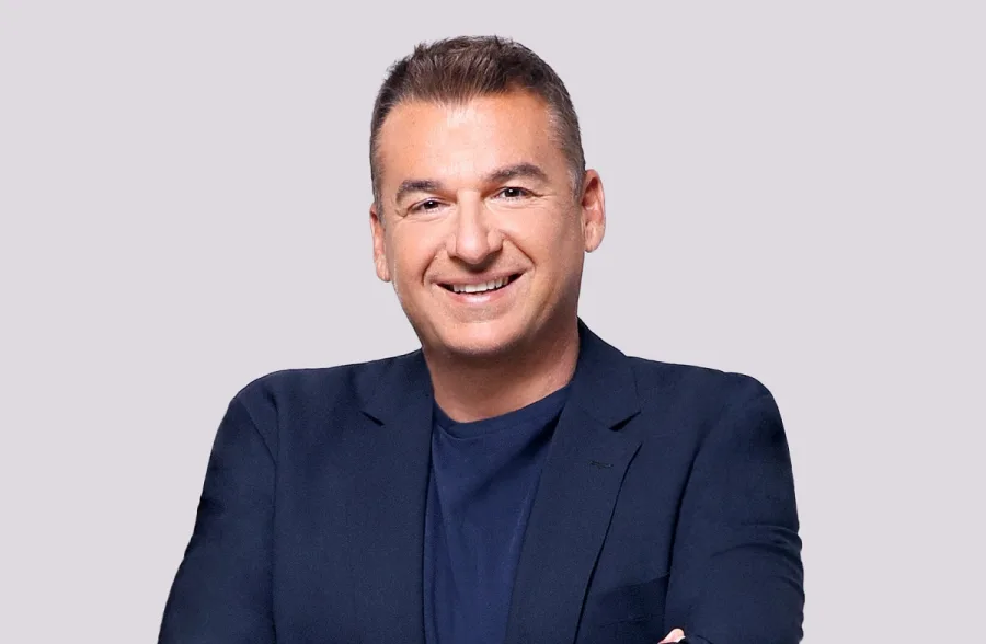 Ο Γιώργος Λιάγκας χαμογελαστός σε στούντιο.