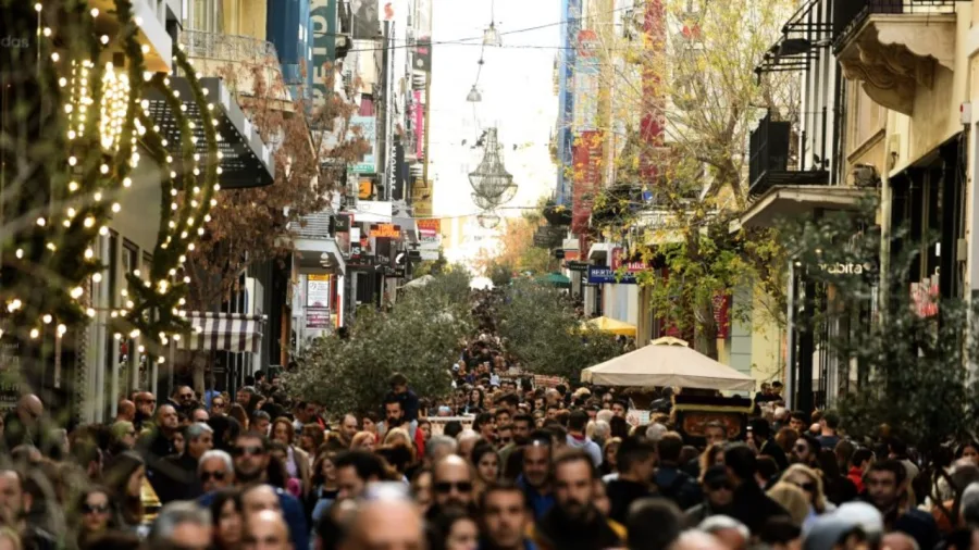 Πλήθος κόσμου σε εμπορικό δρόμο της Αθήνας με χριστουγεννιάτικο διάκοσμο.