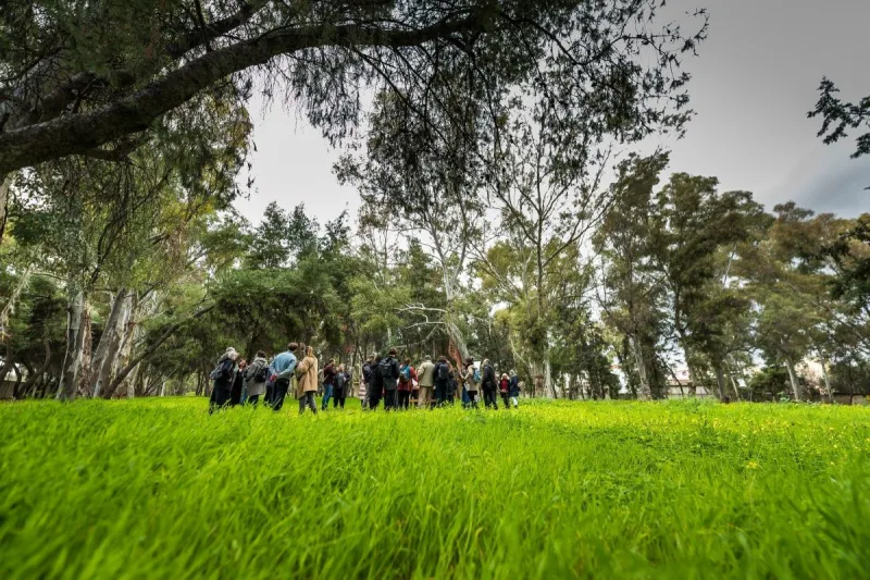 Ομάδα ανθρώπων σε καταπράσινο λιβάδι με δέντρα στην Ελευσίνα.