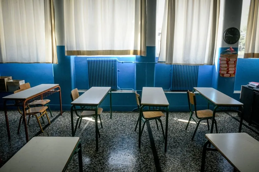 Άδεια σχολική αίθουσα με θρανία και καρέκλες.