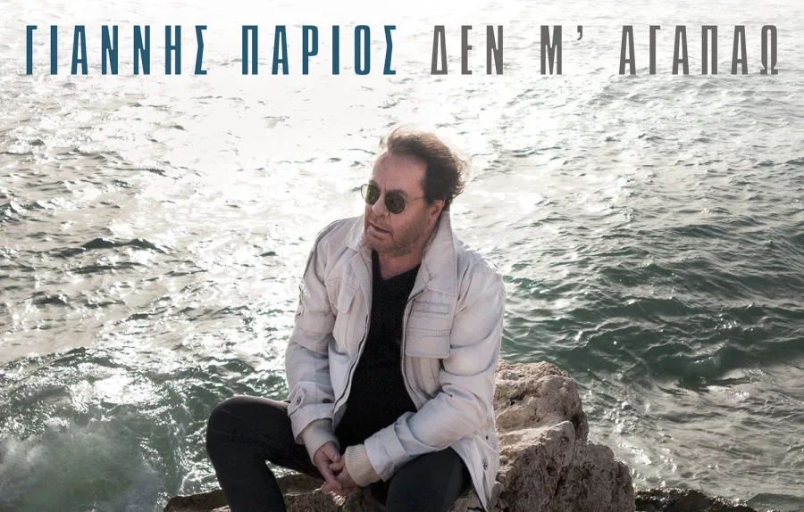 Ο Γιάννης Πάριος κάθεται σε βράχια δίπλα στη θάλασσα.