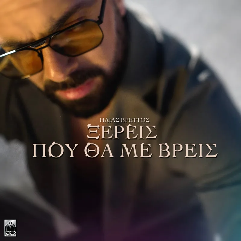Ο Ηλίας Βρεττός με γυαλιά ηλίου και μούσι σε κοντινό πλάνο.