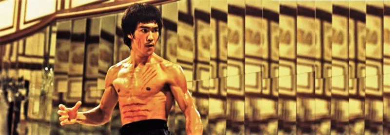 Ο Bruce Lee με σημάδια στο στήθος σε αίθουσα με καθρέφτες.