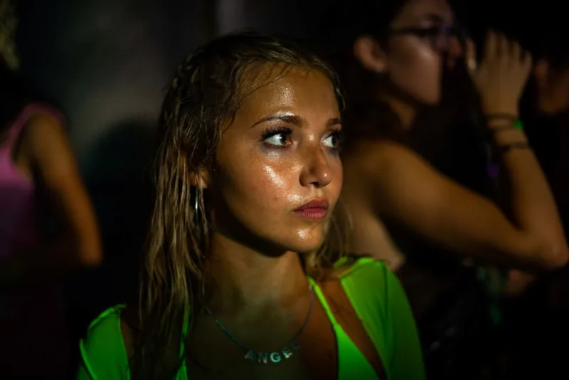 Κοντινό πλάνο νεαρής γυναίκας με βρεγμένα μαλλιά και έντονο βλέμμα σε νυχτερινό περιβάλλον.