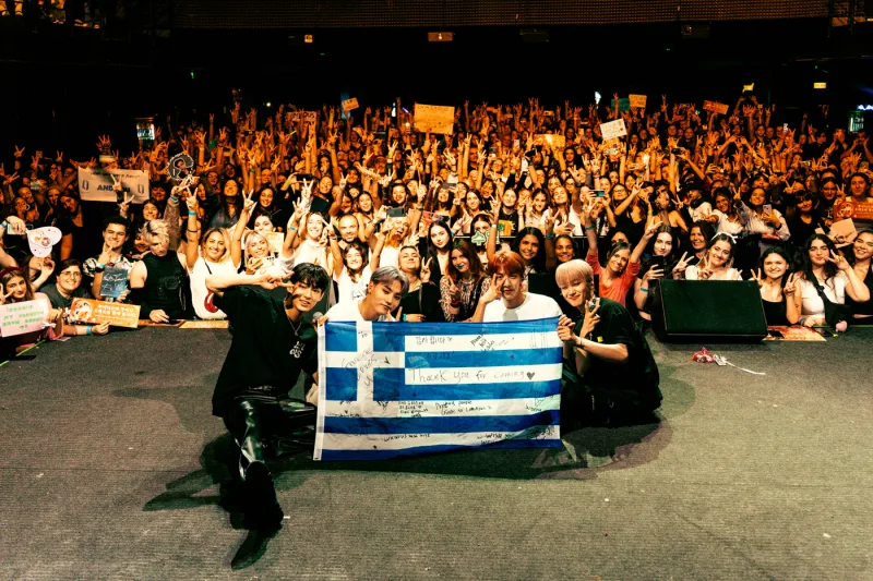 Το K-pop συγκρότημα LUMINOUS ποζάρει με θαυμαστές και την ελληνική σημαία.