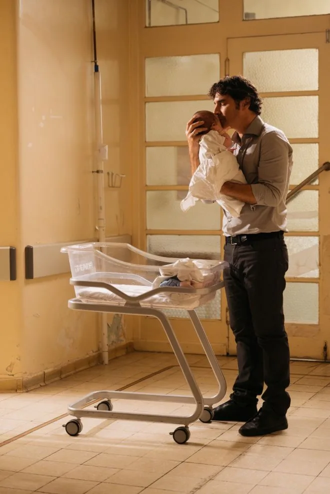 Ο Χριστόφορος Παπακαλιάτης κρατά ένα μωρό σε νοσοκομείο.