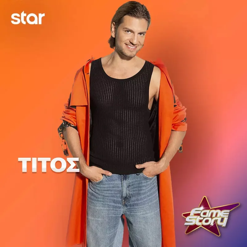 Ο Τίτος από το Fame Story ποζάρει με μαύρο αμάνικο μπλουζάκι και πορτοκαλί πανωφόρι.