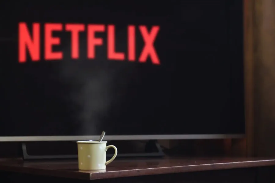 Τηλεόραση που δείχνει το λογότυπο του Netflix και μια κούπα με αχνιστό ρόφημα.