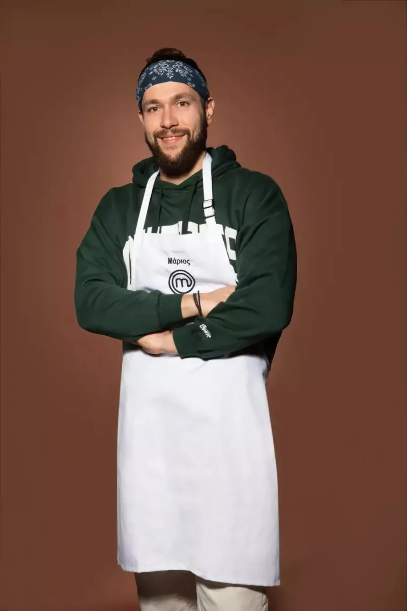 Ο Μάριος, διαγωνιζόμενος του MasterChef, με λευκή ποδιά και πράσινο φούτερ.