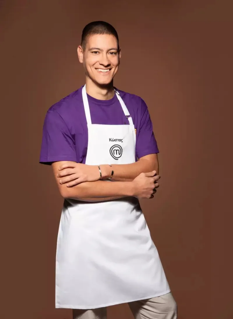 Ο Κώστας, παίκτης του MasterChef, με λευκή ποδιά και μωβ μπλουζάκι.
