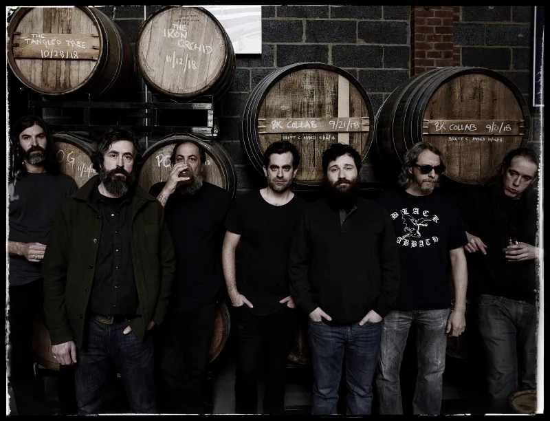 Το συγκρότημα The Budos Band ποζάρει μπροστά από ξύλινα βαρέλια.